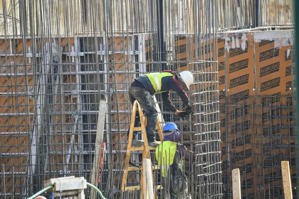 Workers building rebar walls on a job site